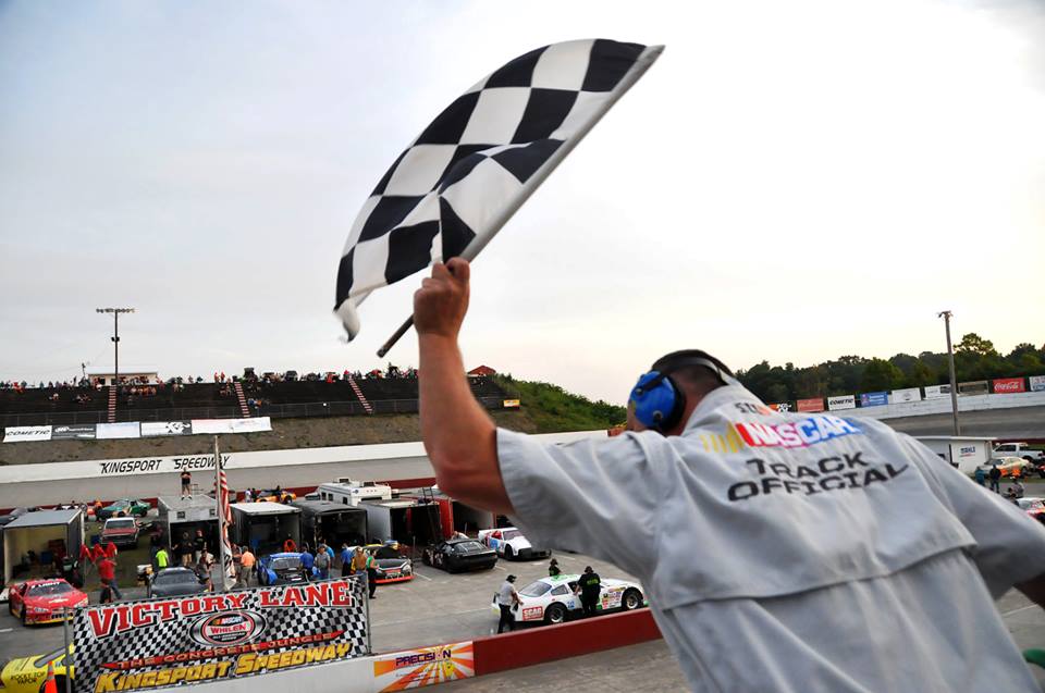 A track official waving the checkered flag at the end of a race at kingsport speedway